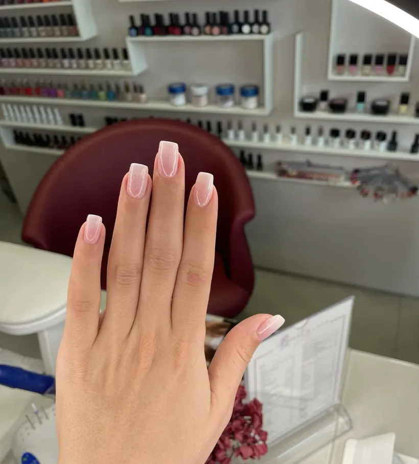 Manucure russe avec dégradé ombré, devant le mur de vernis