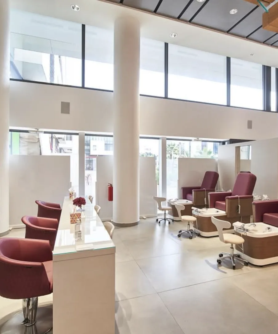La salle du rez-de-chaussée de The Beauty Loft, mur de vernis et fauteuils de pédicure sous la double hauteur
